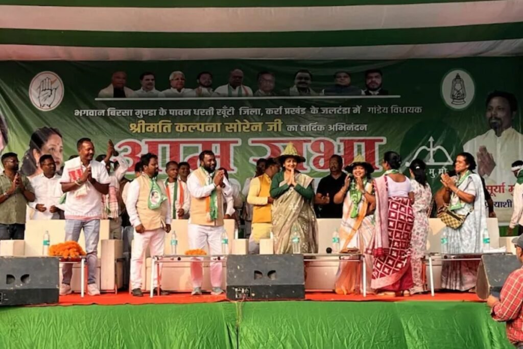 Kalpana Soren delivering a speech at a Jharkhand election rally, with a large crowd of women and tribal voters attending