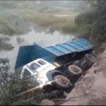 HGV truck falling into river after breaking bridge railing in Saraikela, driver safe, rescue operation underway.