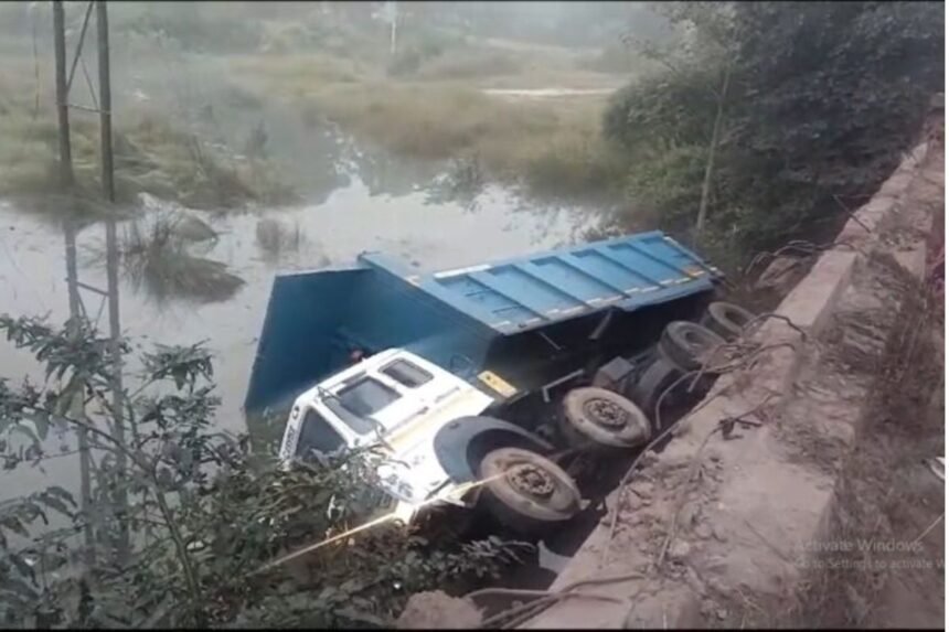 HGV truck falling into river after breaking bridge railing in Saraikela, driver safe, rescue operation underway.