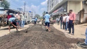 Workers and BJP volunteers fill potholes on a damaged road in Hazaribagh